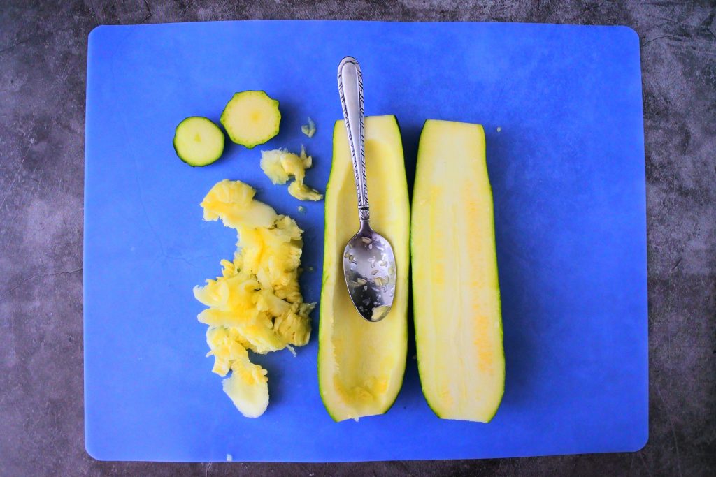 An overhead image of a zucchini that's had both ends removed, sliced in half and the insides scooped out