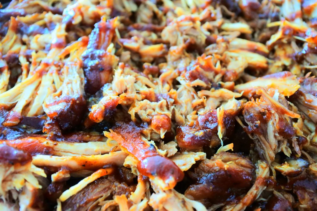A close up image of pulled pork shredded with bbq sauce over it.