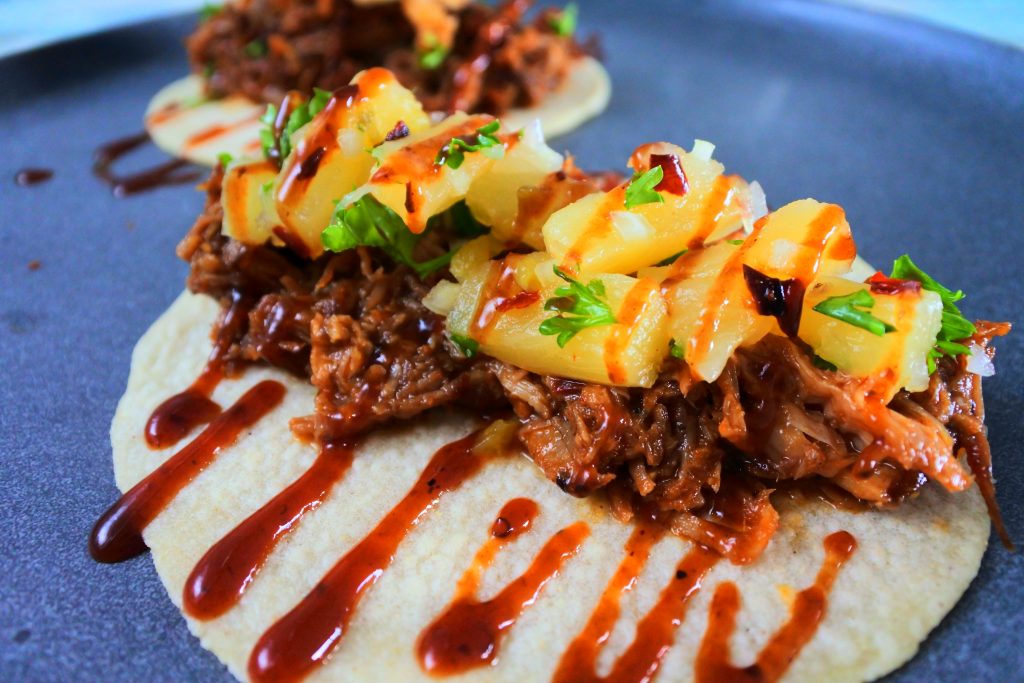 A head on image of a BBQ pulled pork taco topped with pineapple salsa