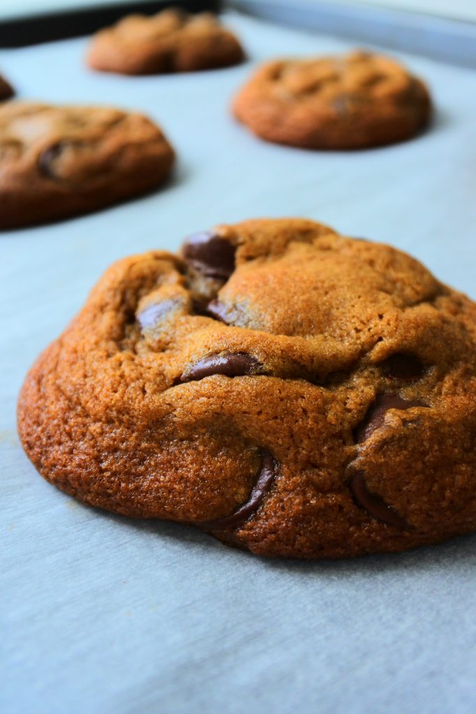 A close up image of a baked classic chocolate chip cookie on a tray
