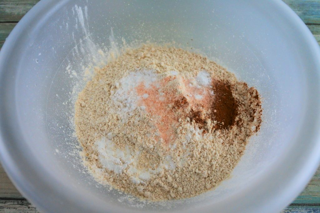 An angled image of whole wheat pastry flour, baking powder, baking soda, salt and cinnamon in a bowl