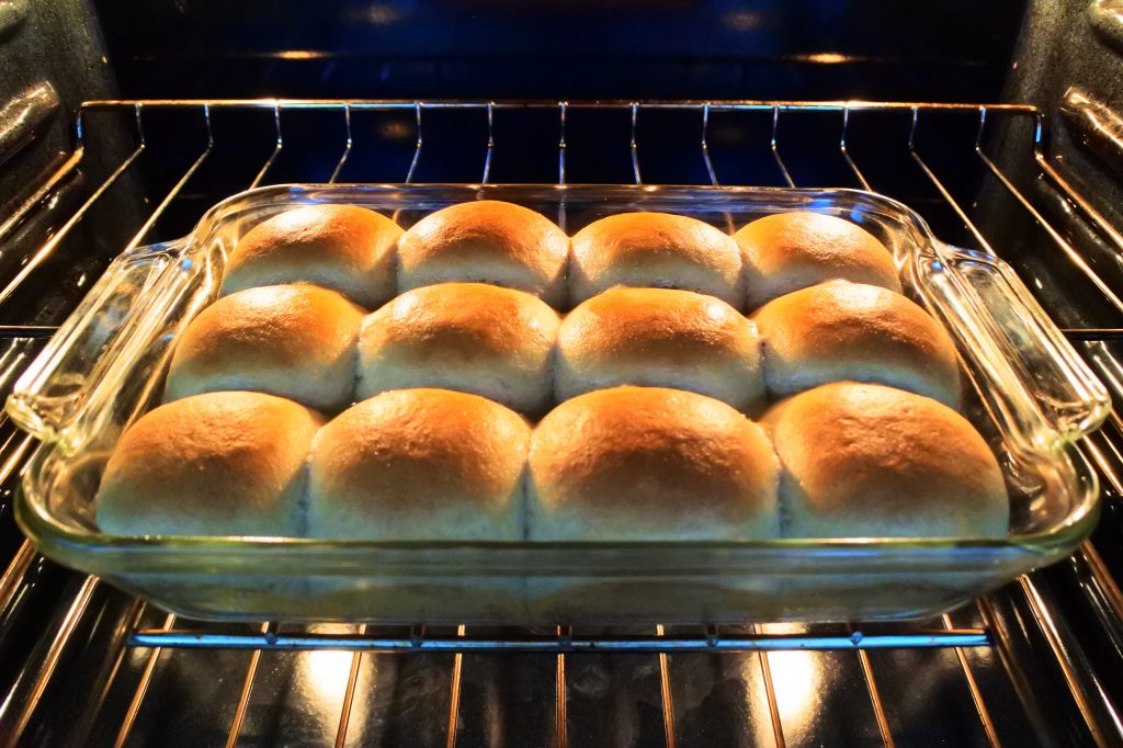 An angled image of freshly baked dinner rolls in a baking dish in the oven