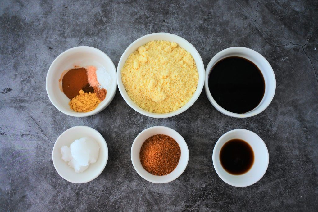 An image of ingredients for gingersnap cookies including spices, almond flour, molasses, coconut oil, coconut sugar, and vanilla extract