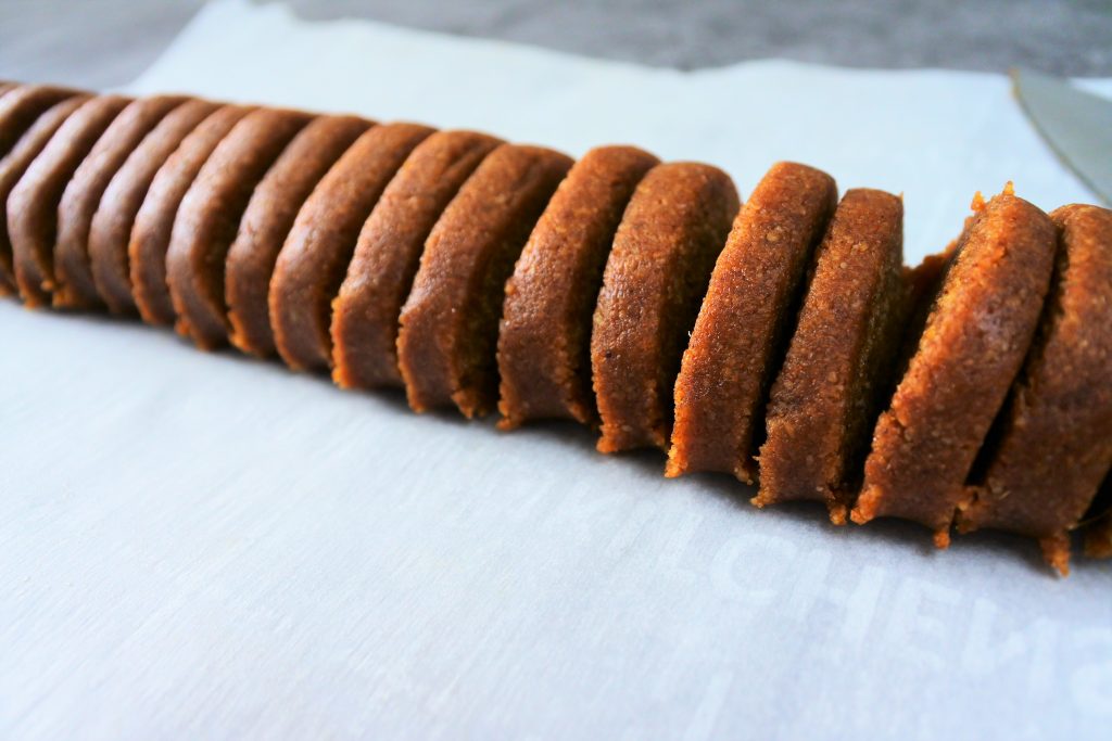 A close up image of a log of gingersnap cookie dough sliced into rounds