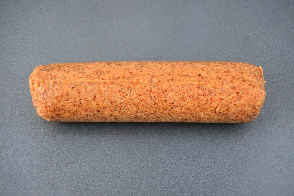 An overhead image of a chilled log of gingerbread cookie dough on a baking tray