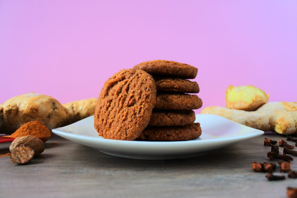 An head on image of a stack of gingerbread cookies surrounded by spices