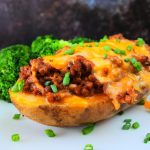 A headon image of a loaded cheesy meat stuffed baked potato