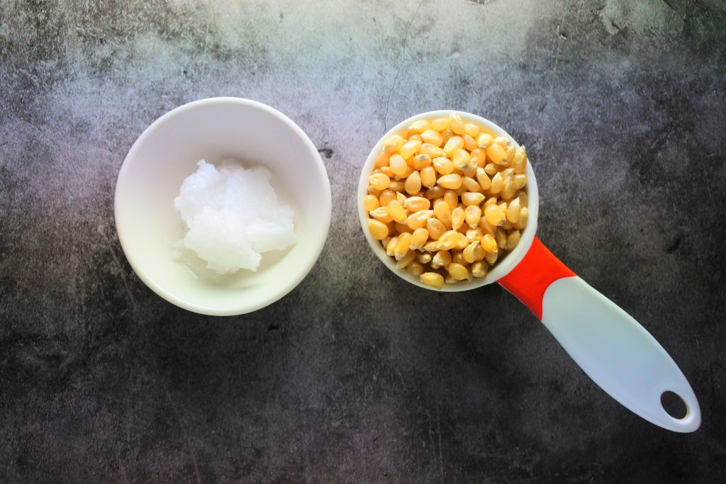 An overhead image of coconut oil and popcorn kernels