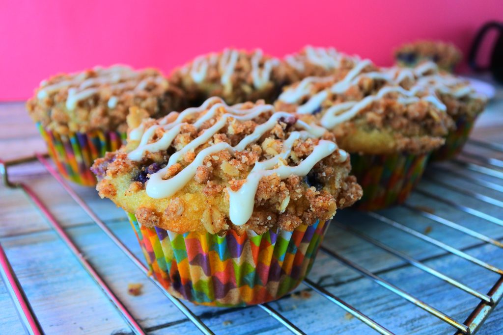 A head on image of a blueberry streusel muffin with a simple stripe of vanilla glaze on top