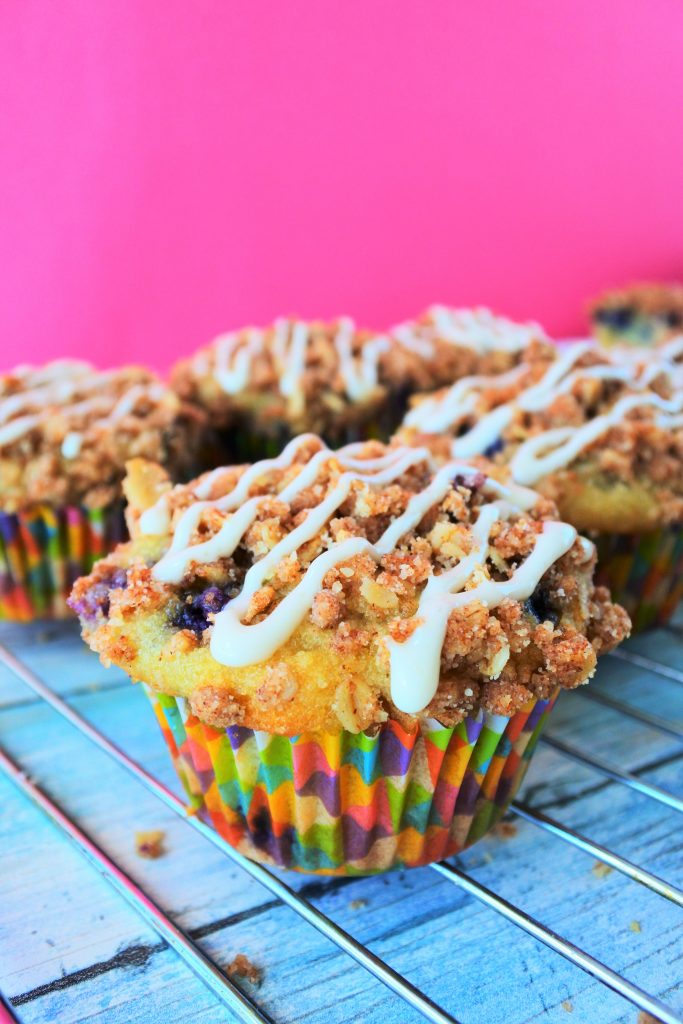 A head on image of a blueberry streusel muffin with a simple stripe of vanilla glaze on top