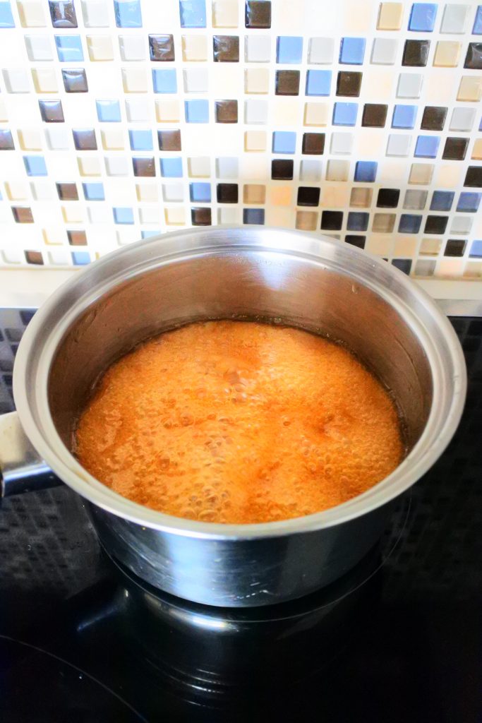 An angled image of a saucepan of simmering ginger candy syrup