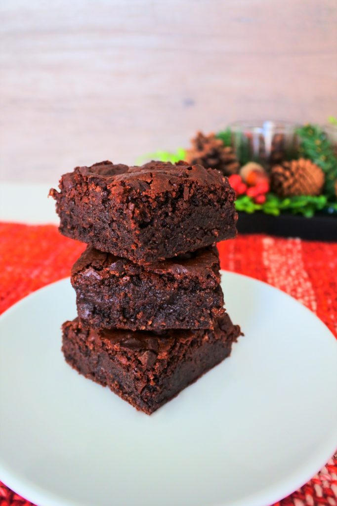 A head on stack of three chewy gluten free brownies on a plate