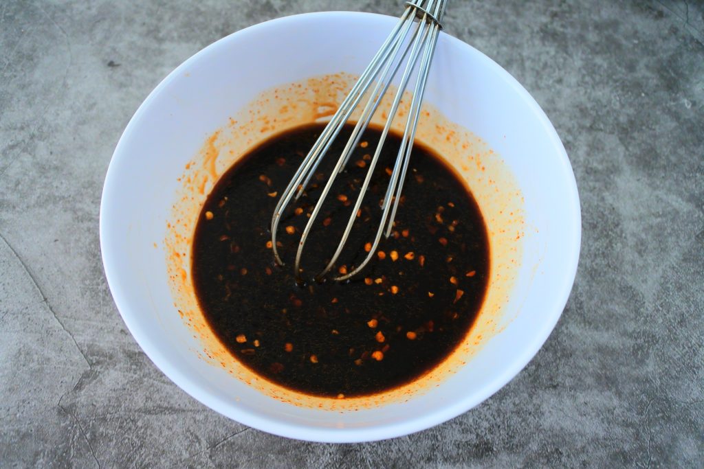 An angled overhead image of a bowl of ingredients for the sauce for a teriyaki beef bowl being whisked together.