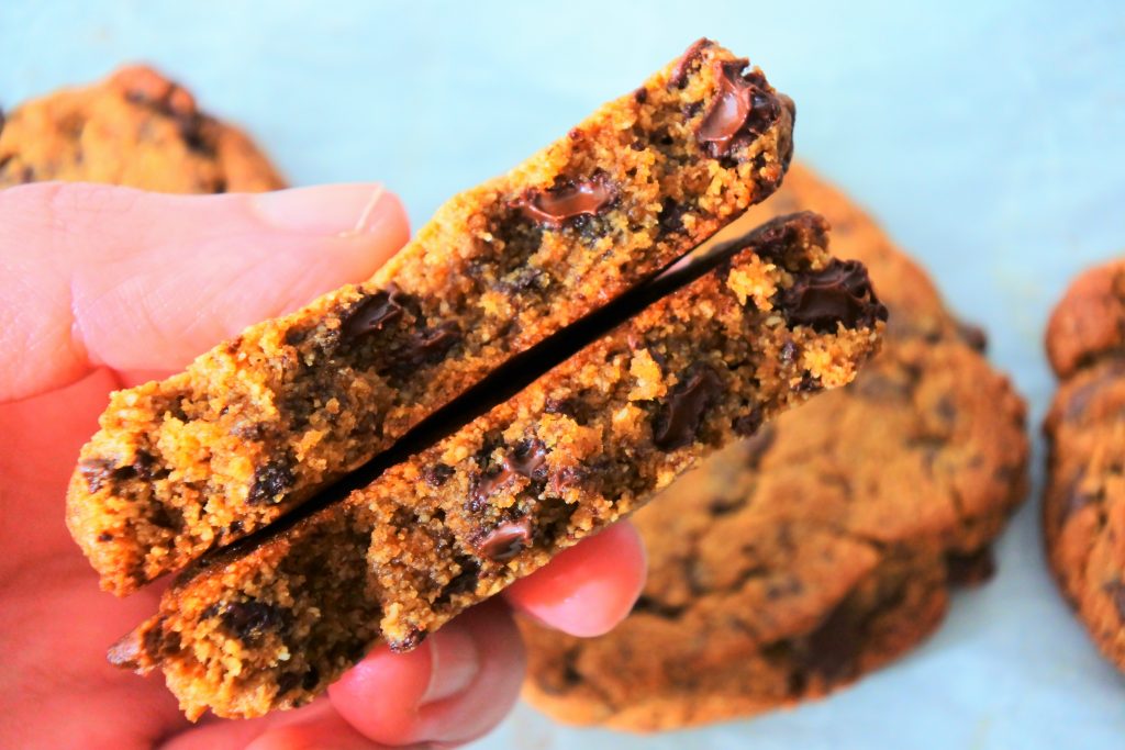 A close up image of a freshly baked gluten free chocolate chip cookie being broken in half