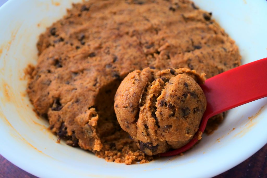 An angled image of a bowl of gluten free chocolate chip cookie dough after being rested for 24 hours in the fridge with a portion scooped out