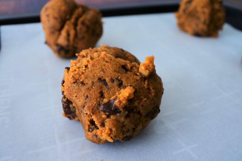 An image of scooped portioned gluten free chocolate chip cookie dough on a parchment lined tray