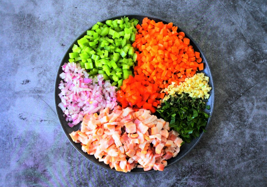 A plate of small diced fresh vegetables and herbs and bacon