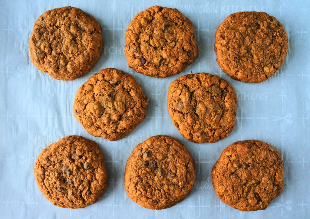 An overhead image of a parchment lined tray of oatmeal chocolate chip cookies