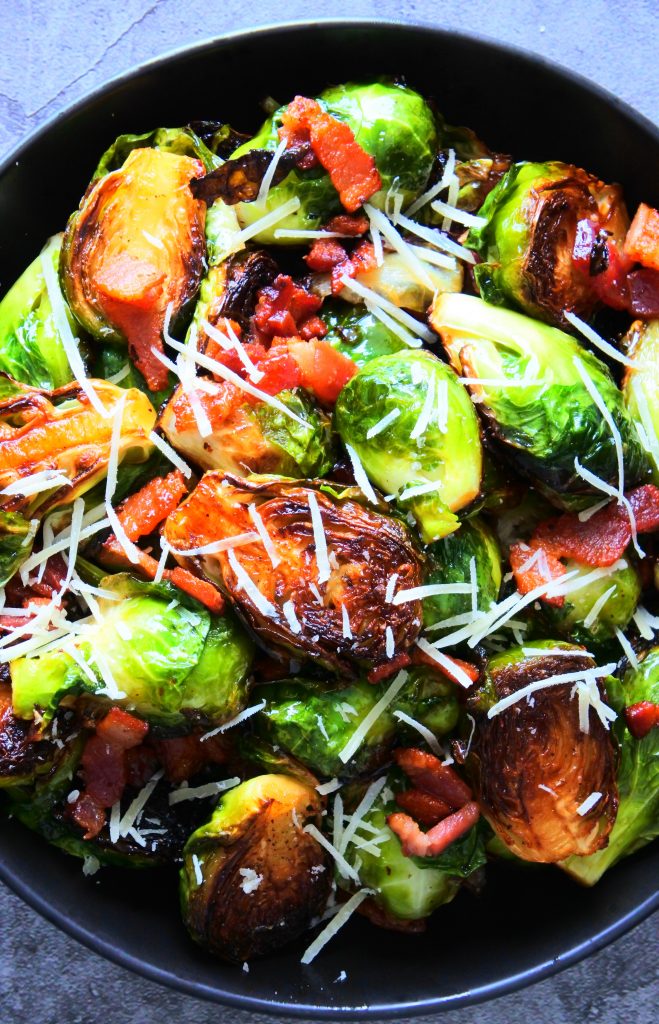 An overhead image of a dish of maple bacon brussels sprouts topped with finely shredded cheese