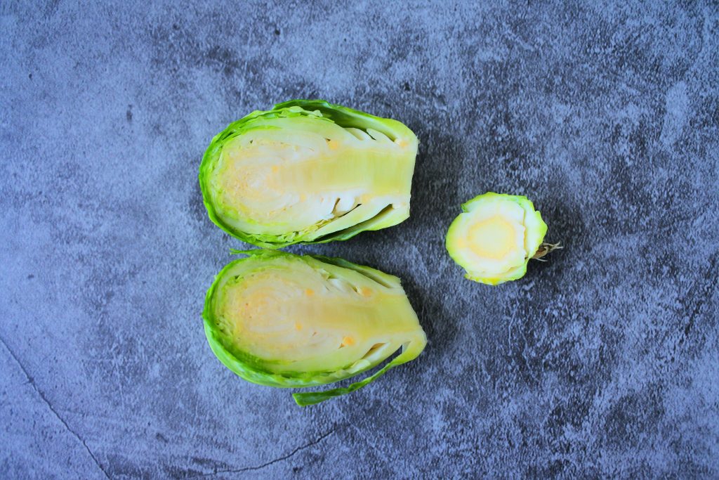 An overhead image of a halved fresh brussels sprout with the end cut off