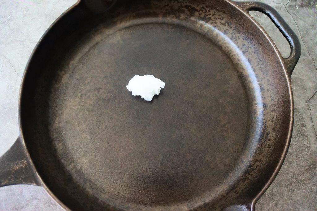 An overhead image of a skillet with a bit of unmelted coconut oil in it