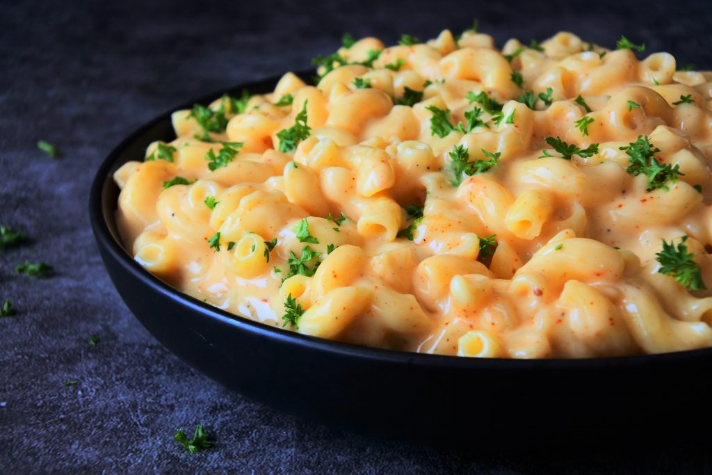A close up image of homemade mac and cheese topped with chipped herbs.