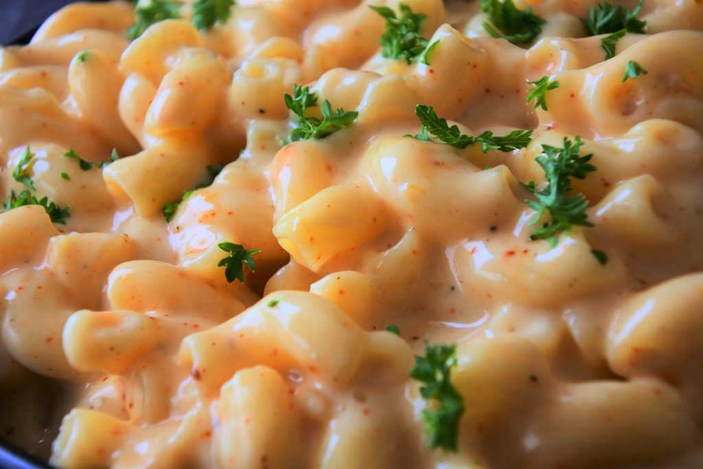 A close up image of homemade mac and cheese topped with chipped herbs.