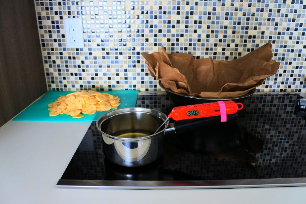 A head on image of the fry station set up for plantain chips including a saucepan of oil being brought up to 350F