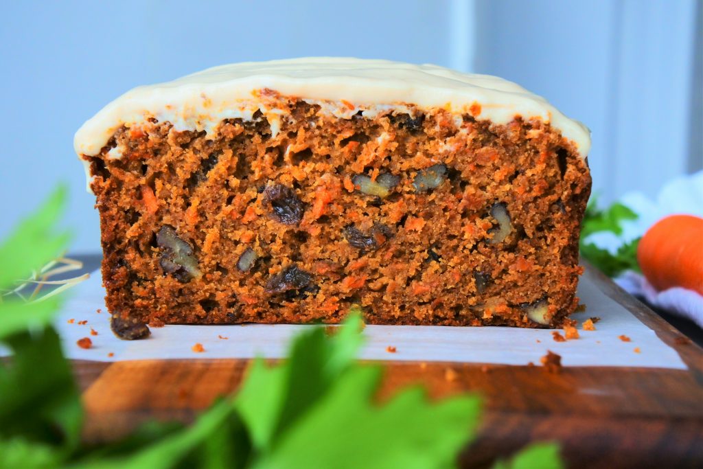 A head on image of a sliced carrot cake loaf on a wooden board