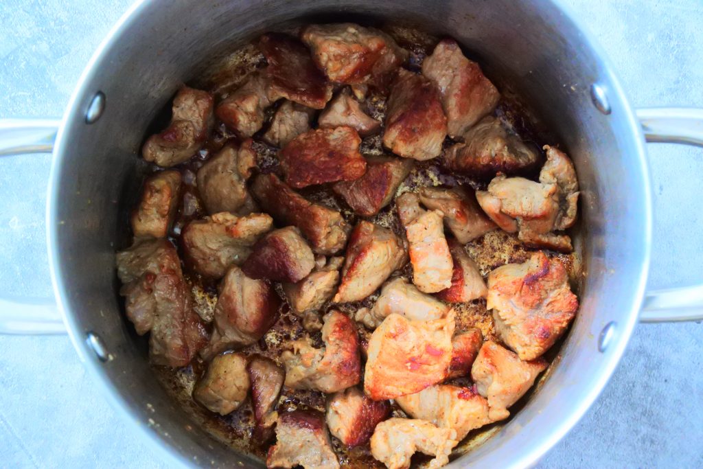 An overhead image of a pot of seared veal chunks.