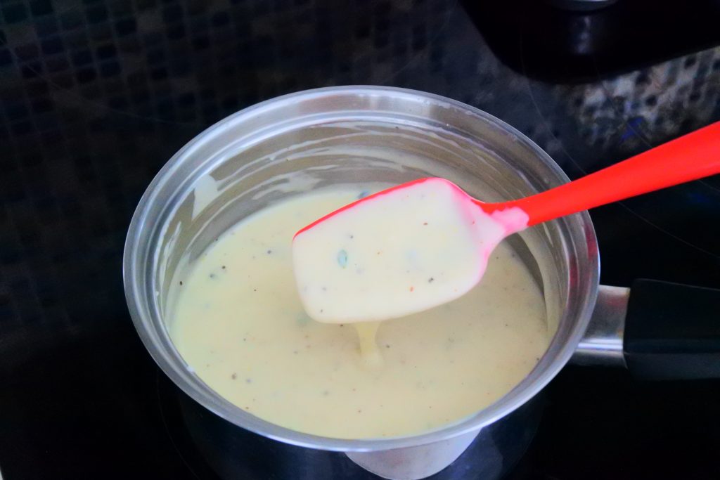 A close up image of a saucepan of thick seasoned Béchamel