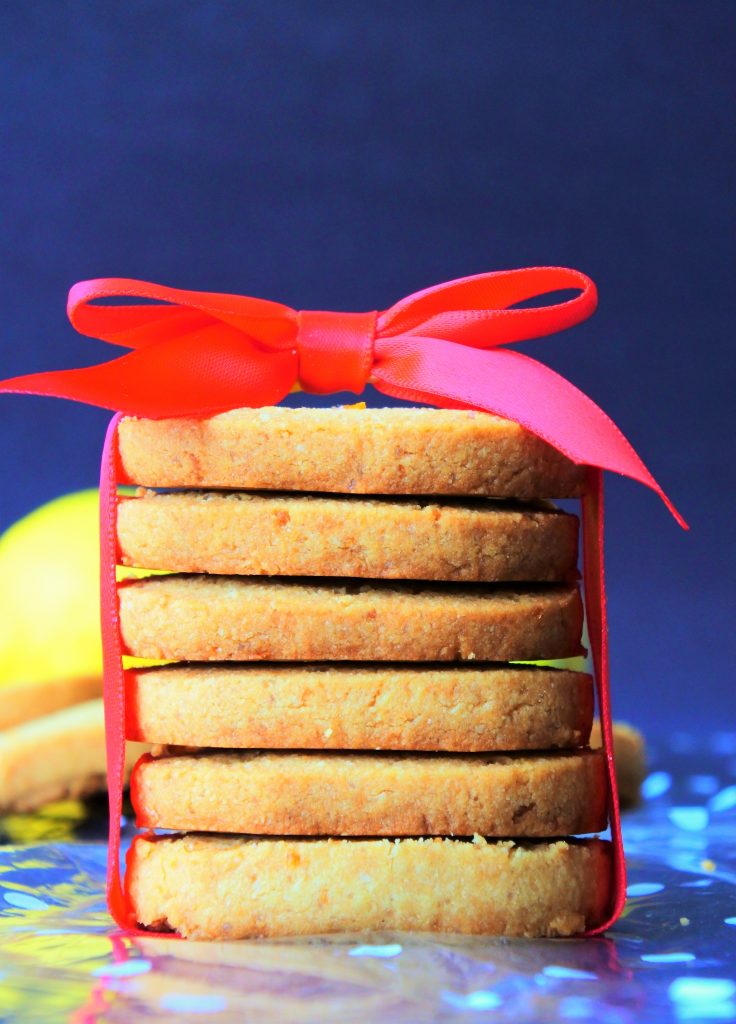 A head on image of a red bow wrapped stack of gluten free lemon shortbread cookies
