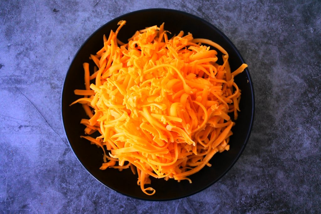 An overhead image of a plate of freshly shredded cheddar cheese.