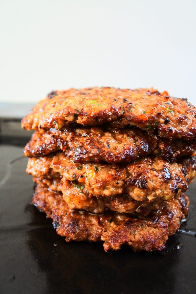 A stack of beef and veg patties after being fried in a cast iron skillet