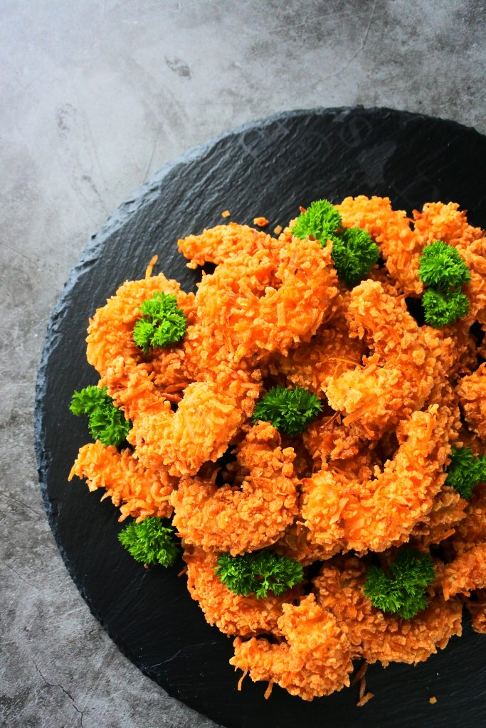 An overhead image of golden fried coconut shrimp on a slate plate