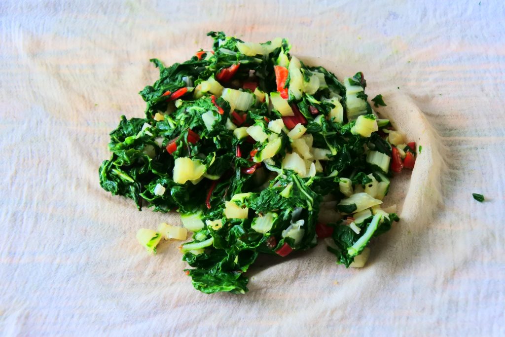 An angled image of blanched swiss chard on a cloth before having the water squeezed out.