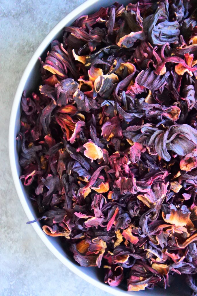 An overhead image of a half a bowl of dried sorrel/roselle flowers