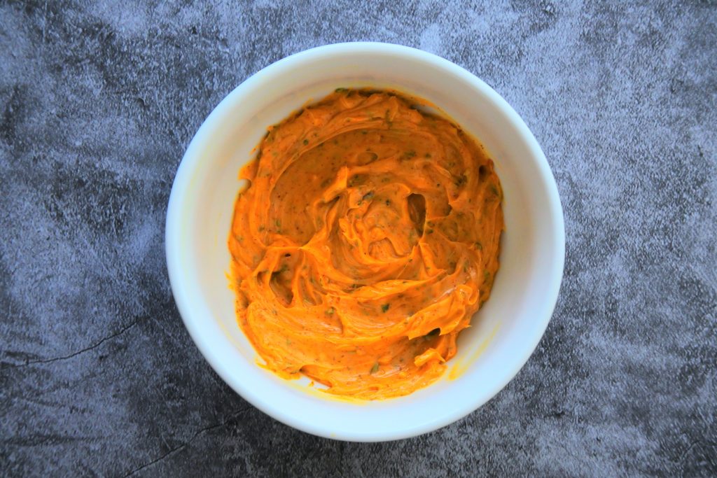 An overhead image of softened, just mixed saffron compound butter in a white bowl