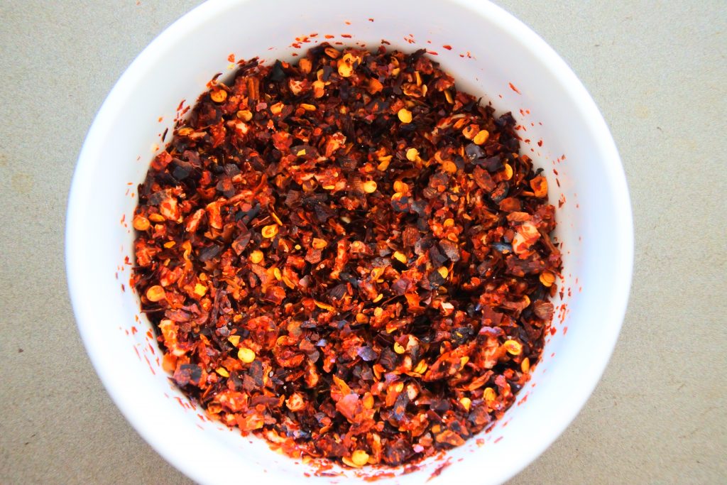 An overhead view of a bowl of red pepper flakes mixed with minced garlic and salt
