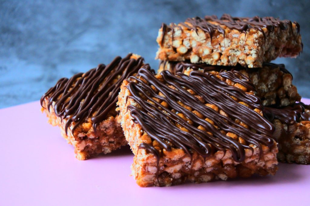 A close up image of a pile of chocolate striped peanut butter rice crispy bars