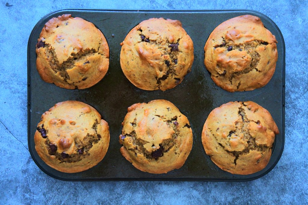 An overhead image of freshly baked chocolate chip coffee muffins in a muffin tin.