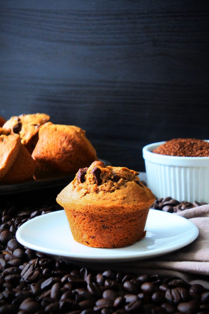 A head on image of a freshly baked warm chocolate chip coffee muffin on a plate