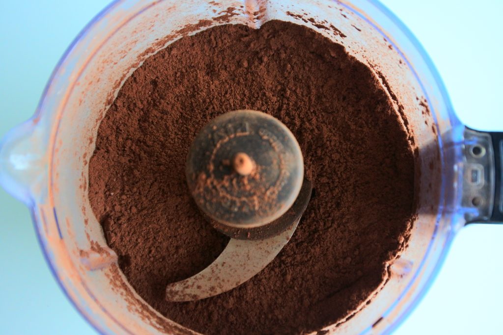 An overhead image of dark chocolate chunks blended into a hot cocoa mix in a food processor