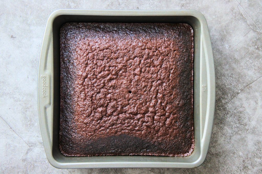 An overhead image of a baked chocolate cake in an 8x8 tin