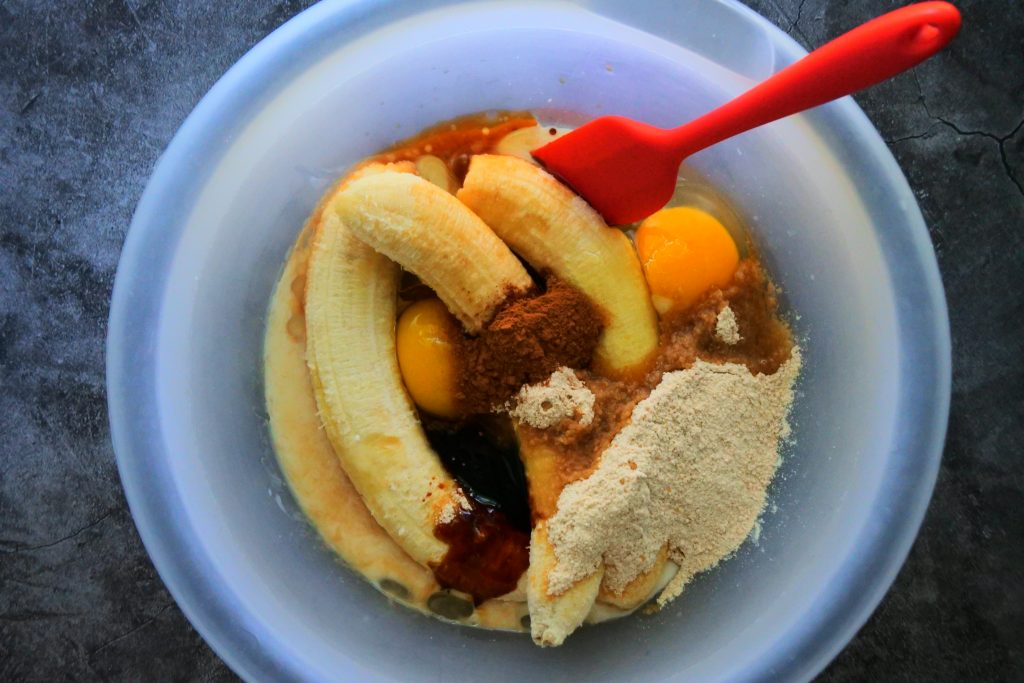 An overhead image of wet ingredients being added to a bowl before being mixed together for a gluten-free banana bread