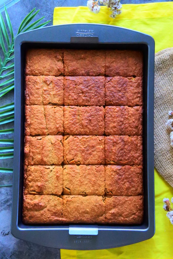 An overhead image of a sheet pan of warm, freshly baked gluten-free banana bread cut into slices