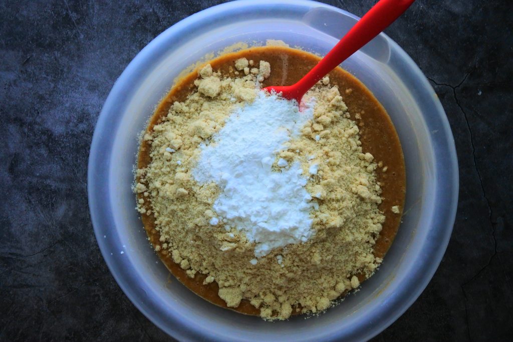An overhead image of dry ingredients being added to the wet ingredients to make a gluten-free banana bread batter.