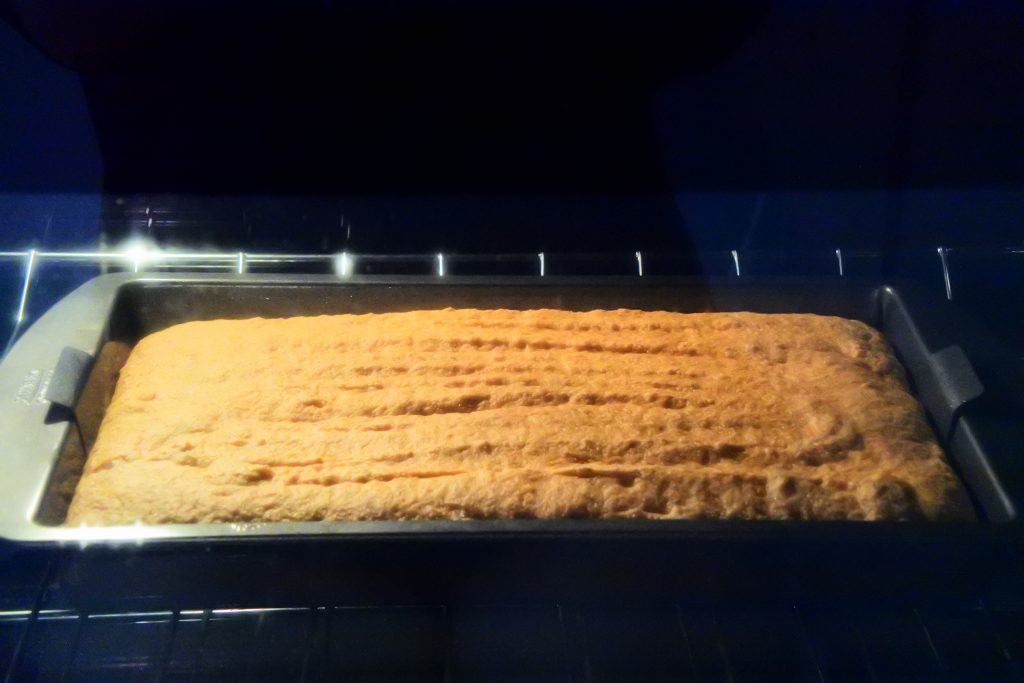 A head on image of a sheet pan of gluten-free banana bread in the oven being baked