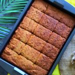 An overhead image of a sheet pan of warm, freshly baked gluten-free banana bread cut into slices