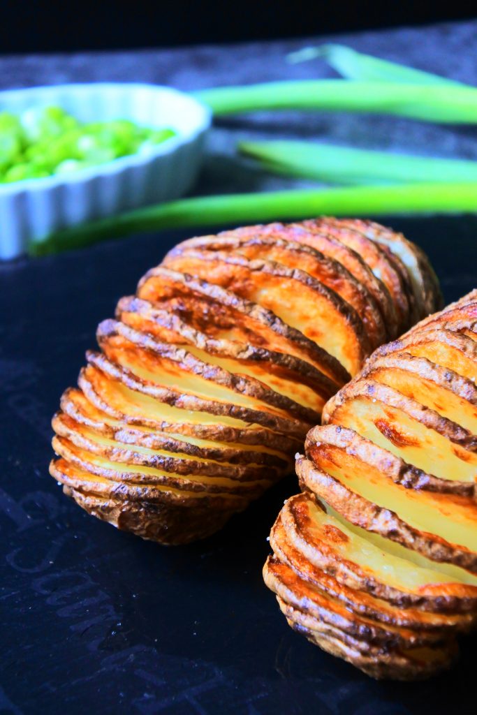 An angled image of crispy Hasselback potatoes on a slate platter